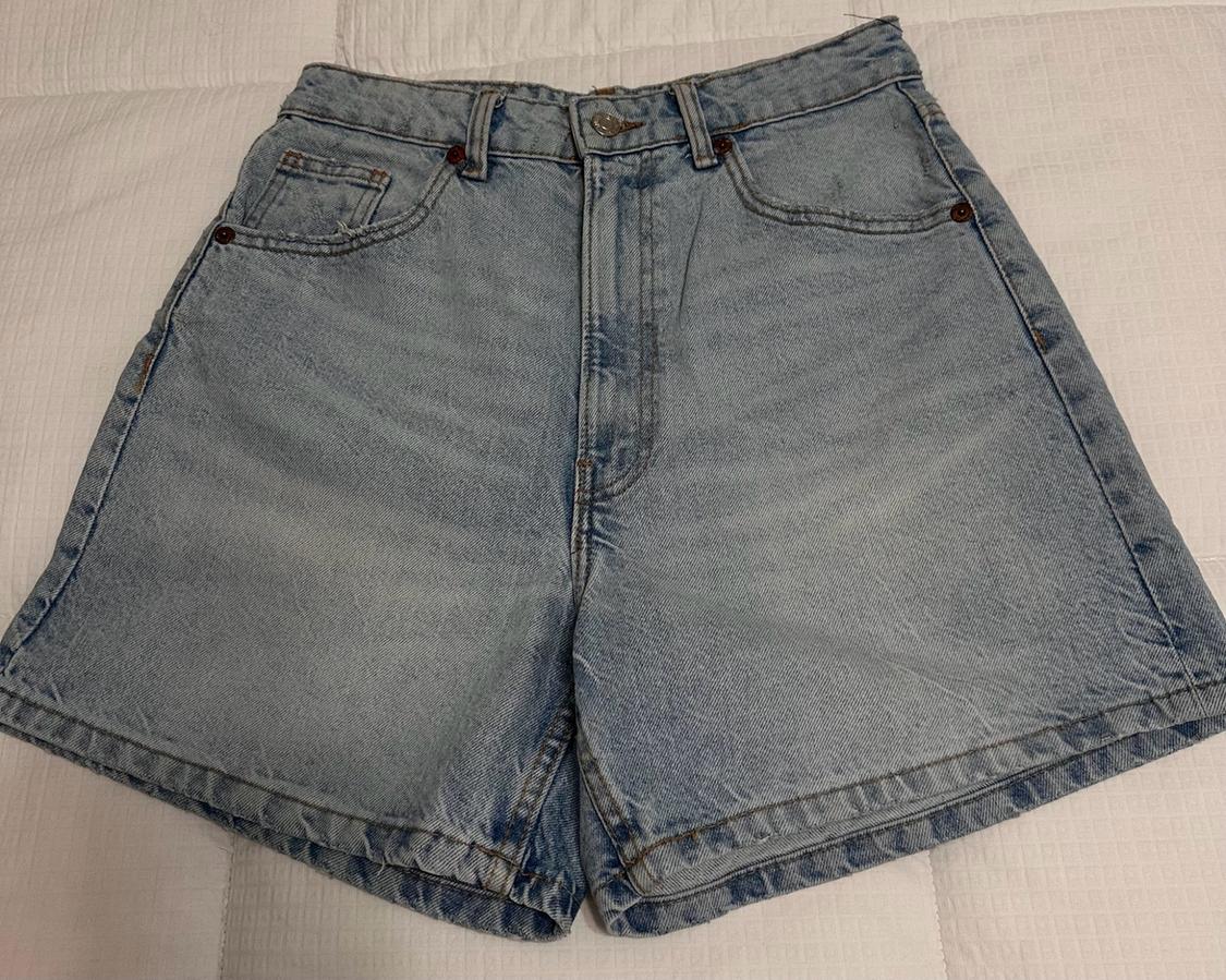 Light-blue high-waisted denim shorts with pockets, on a padded white surface.