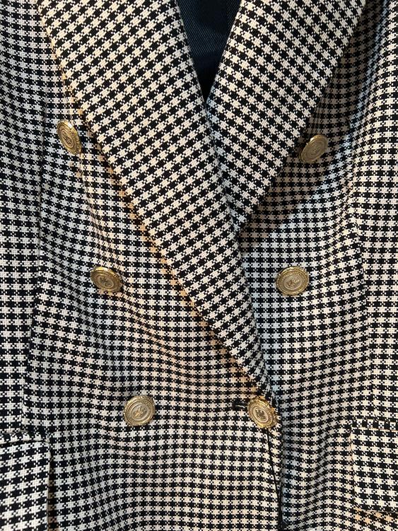 Close-up of a black and white checkered jacket with decorative gold buttons.