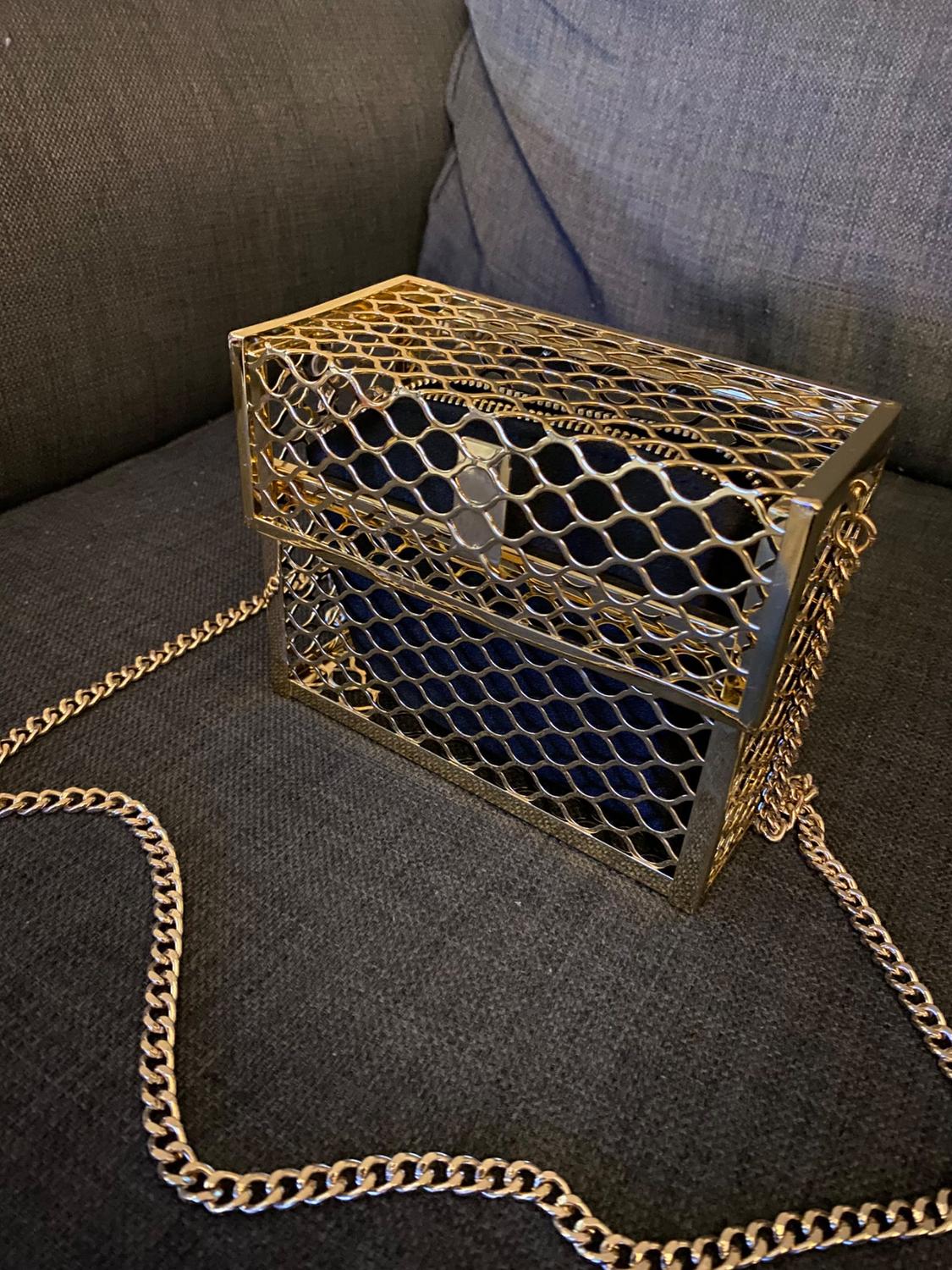 Gold chain handbag with a metal mesh structure and a cross-shaped clasp.
