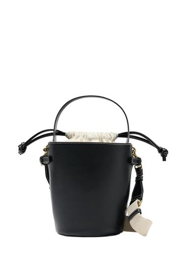 Front view of black bag with drawstring closure and adjustable strap in beige.