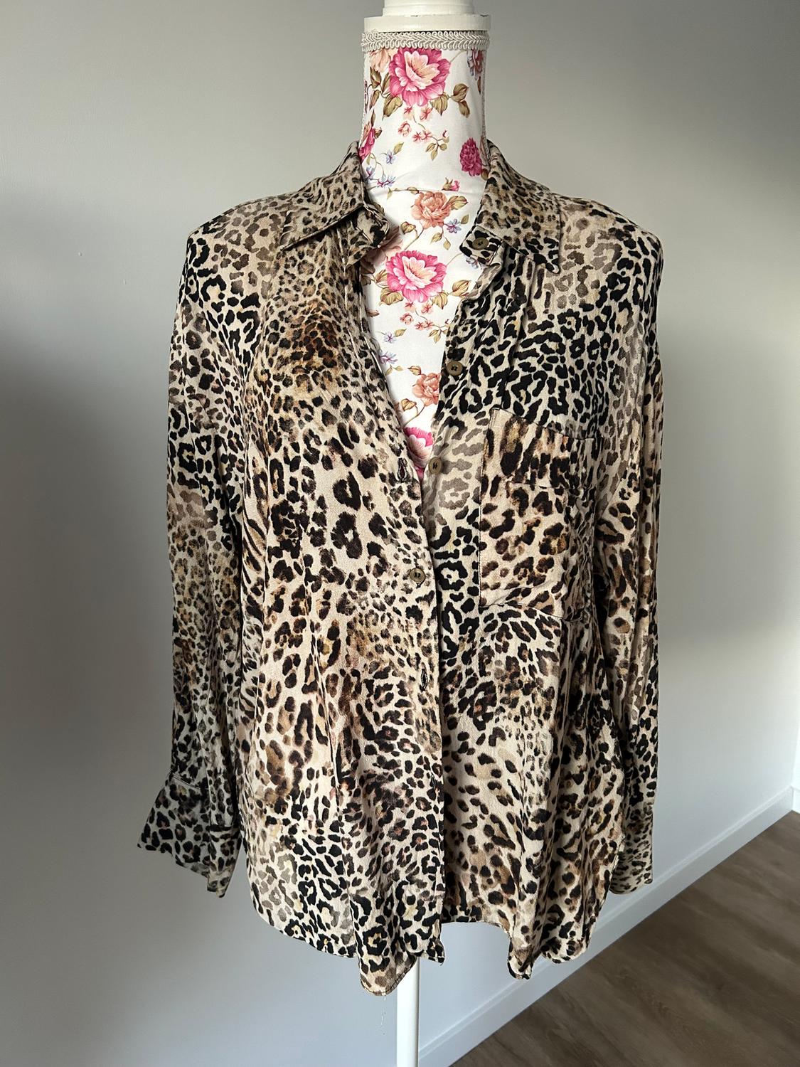 Animal print blouse on a mannequin with floral fabric in the background. The blouse has a loose design and front buttons.