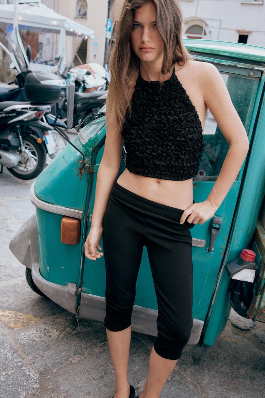 Black halter-neck ruffle crop top and fitted black capri pants set.