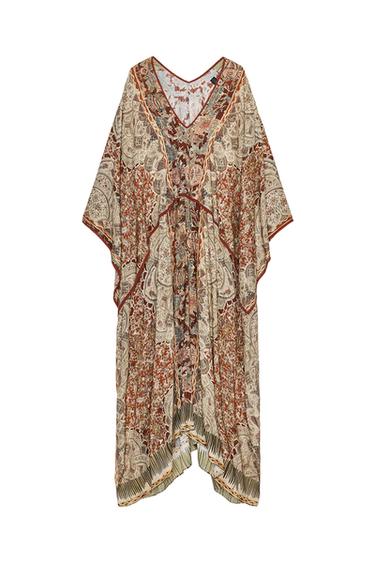 Front view of a long kaftan-style dress with paisley print, V-neck, cape sleeves and an asymmetric hem with slits.