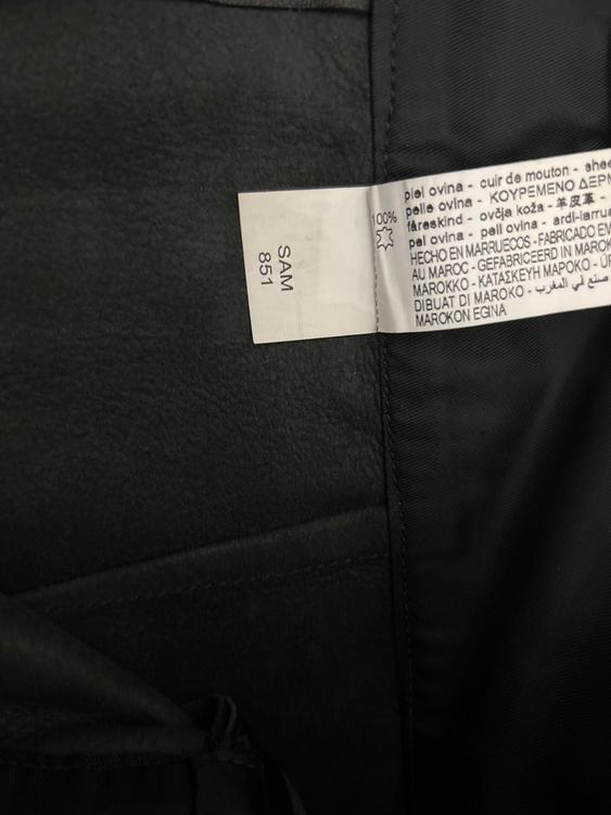 Black fabric label with multi-language text, including "sheepskin" and "Made in Morocco". Visible text: "SAM 851".