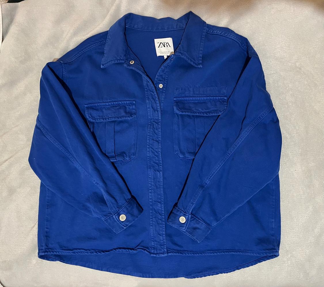 Blue shirt with front pockets and buttons, on a light surface. Visible label with the text "ZARA".
