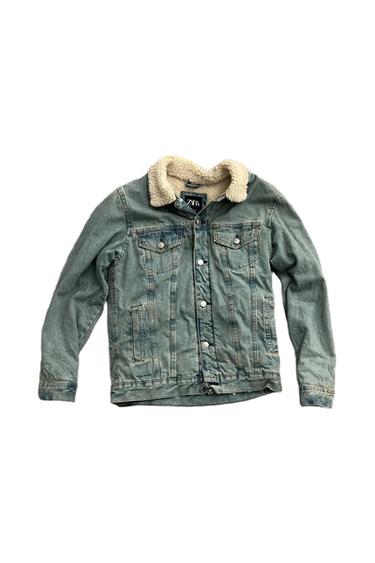 Light blue denim jacket with a white textured collar on a white background. Inside tag with the text ZARA. Casual style.