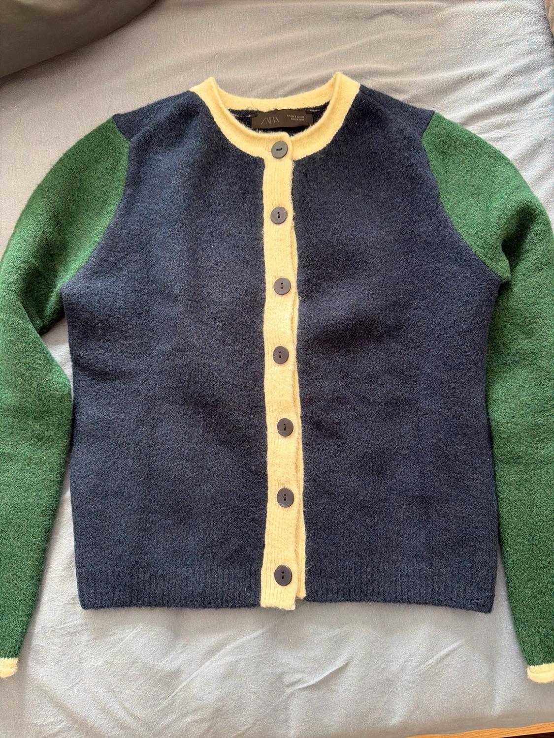 Navy blue knitted cardigan, green sleeves and yellow trims on grey fabric. Button fastening and ZARA label. Casual and relaxed style.