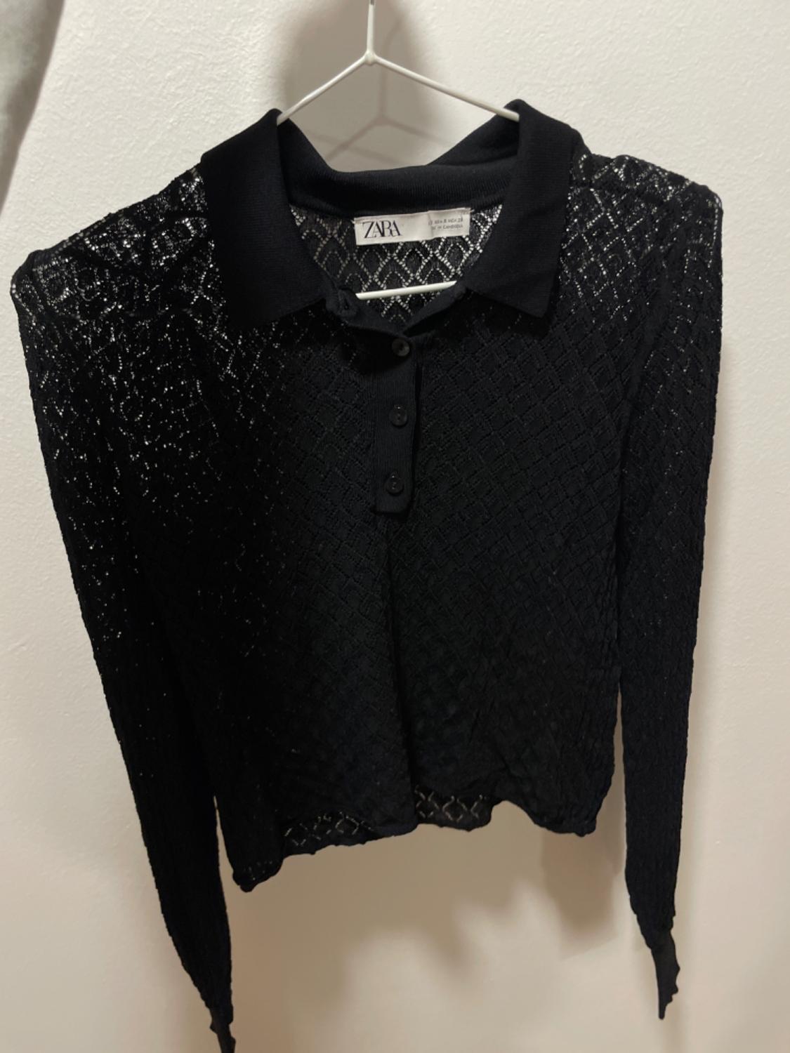 Front view of black lace blouse with collar and button fastening.