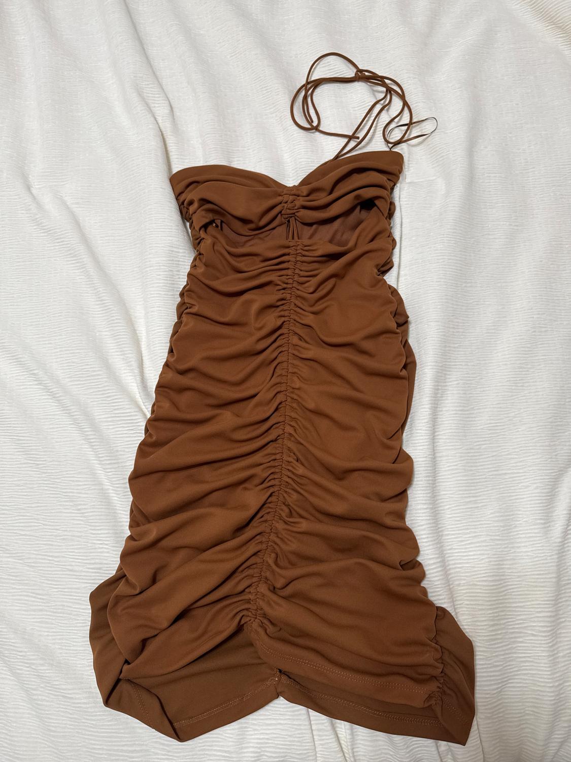Brown ruched dress with spaghetti straps on a white surface. The design is figure-hugging and sleeveless.