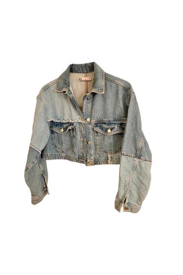 Light blue denim short jacket with front pockets and metallic buttons. Visible label on the collar. White background.