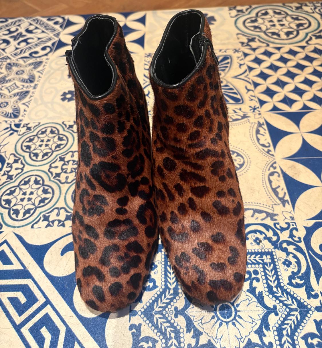 Animal print ankle boots on a tiled floor with geometric and floral patterns in blue and white.