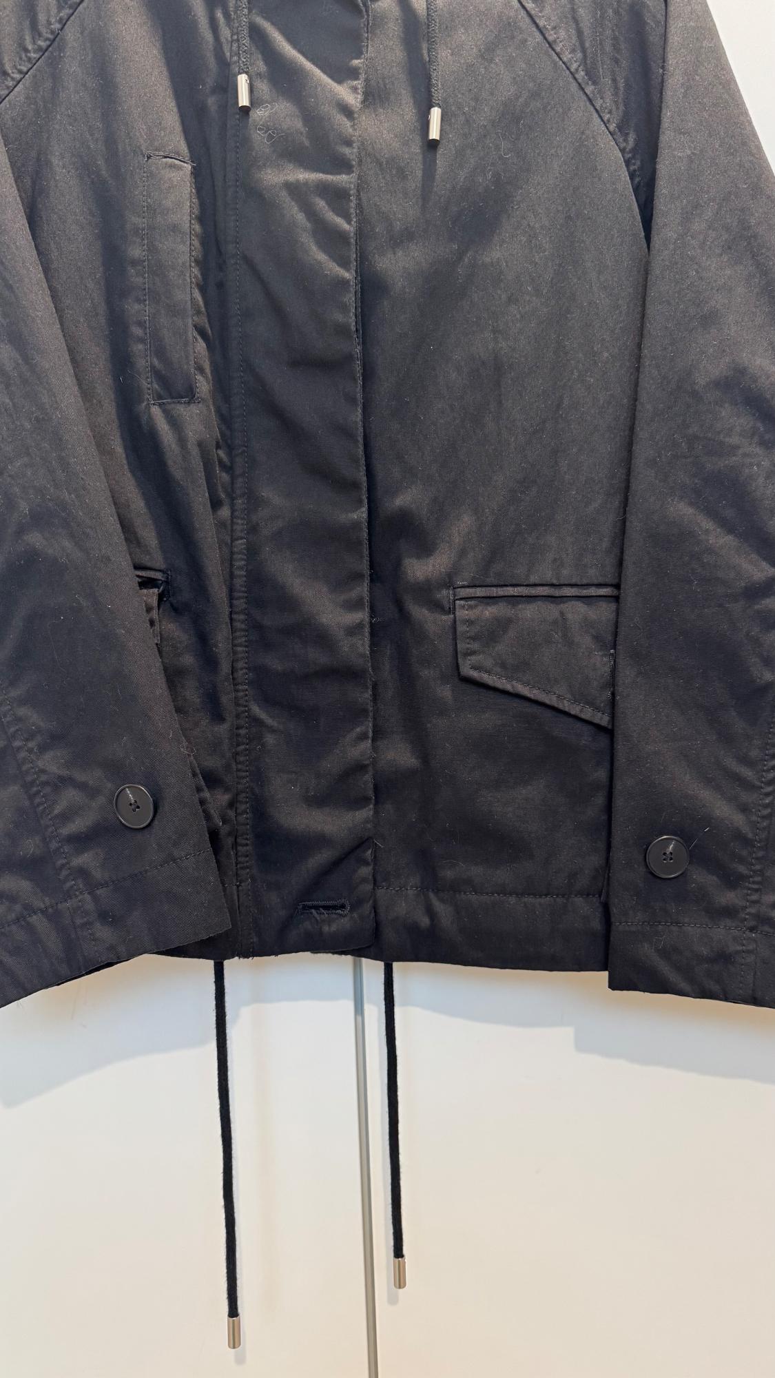 Black jacket with hood and adjustable drawstrings. Large button detail and front pockets. White background.
