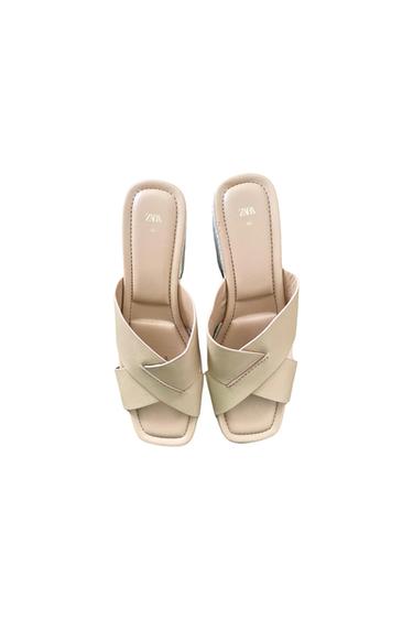 Top view of beige sandals with criss-cross straps and 'ZARA' logo on the insole.