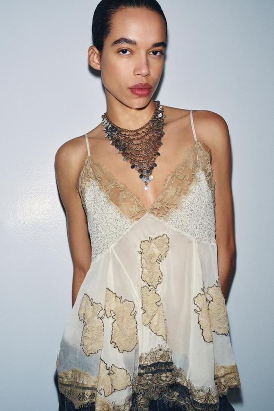 St�edn� detail �erno-b�l�ho krajkov�ho topu s v�st�ihem do V, tenk�mi ram�nky, krajkou a kontrastn� v��ivkou.