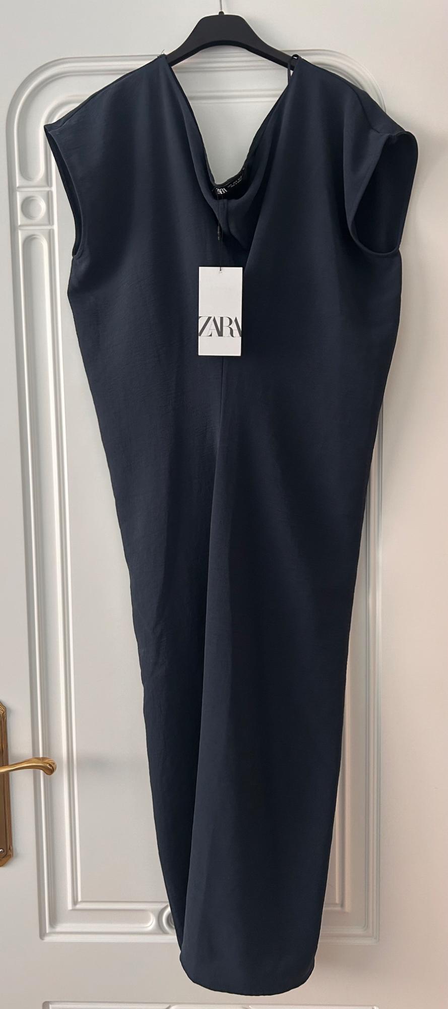 Dark blue, sleeveless dress hanging on a hanger over a white door. Visible label with the text ZARA.