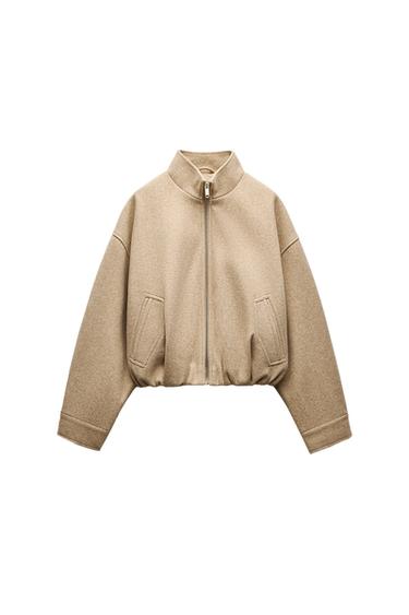 Front view of a beige jacket with a zip and side pockets.