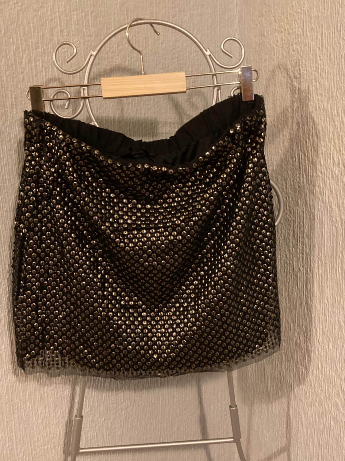 Front view of a black skirt with gold sequins and an elasticated waistband.