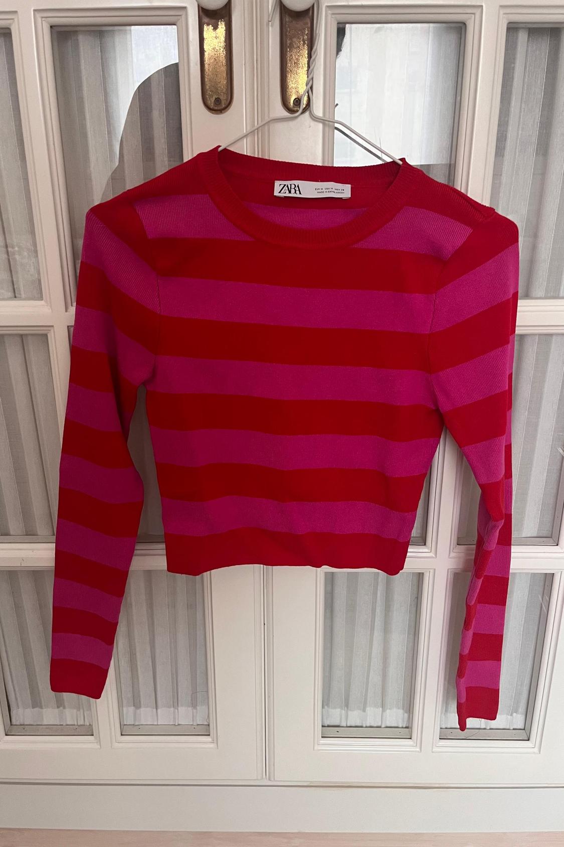 Front view of a striped red and pink jumper with a crew neck.