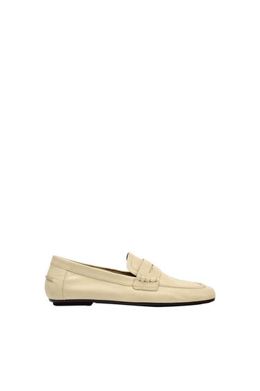 Classic beige loafer with saddle detail, visible stitching and a flat black sole, against a white background.