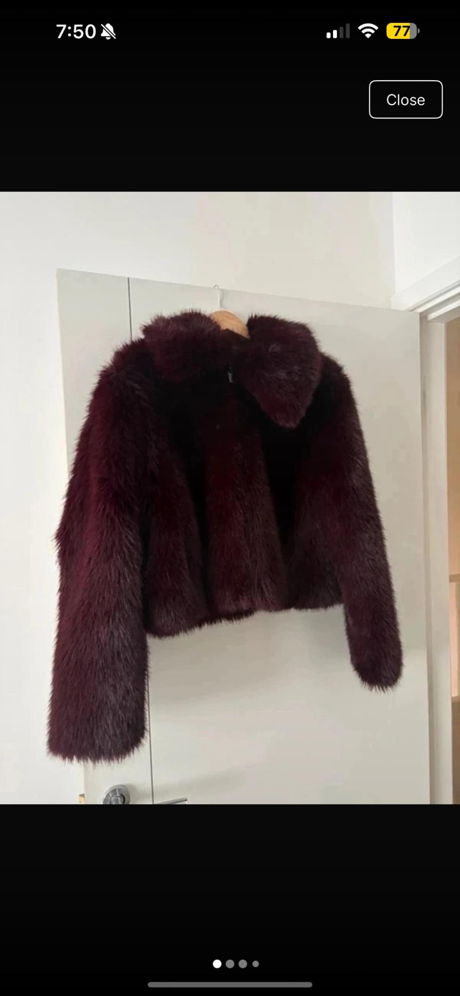 Burgundy-coloured fur jacket hanging on a white door. Text: Close.