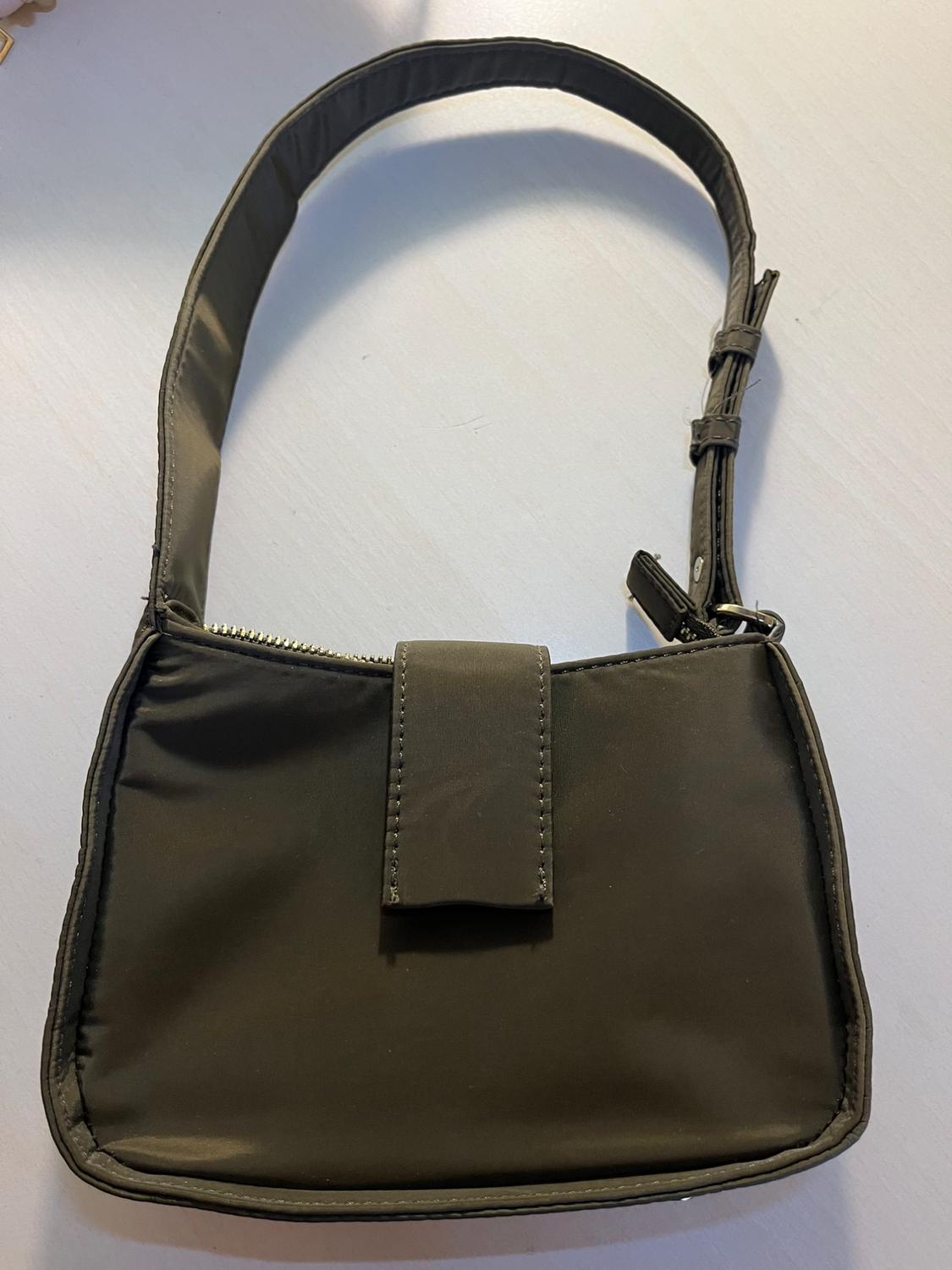Dark olive green shoulder bag with an adjustable strap, top zip fastening and a decorative front flap, set against a light background.