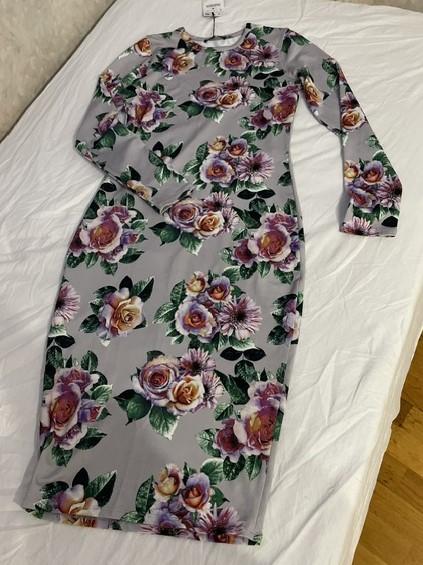 Grey long-sleeved dress with a floral print of purple roses and green leaves, laid out on a white sheet.