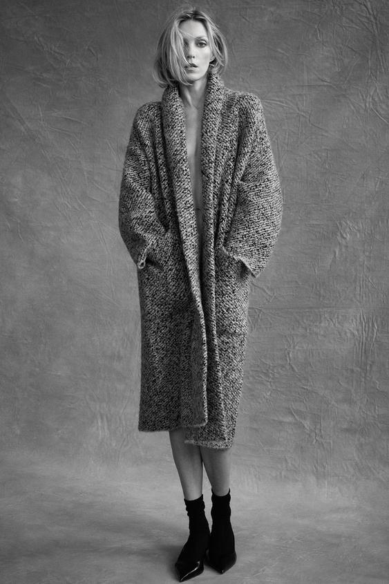 �ed� dlouh� texturovan� kab�t, bo�n� kapsy, �irok� l�mec a �ern� lodi�ky na podpatku.