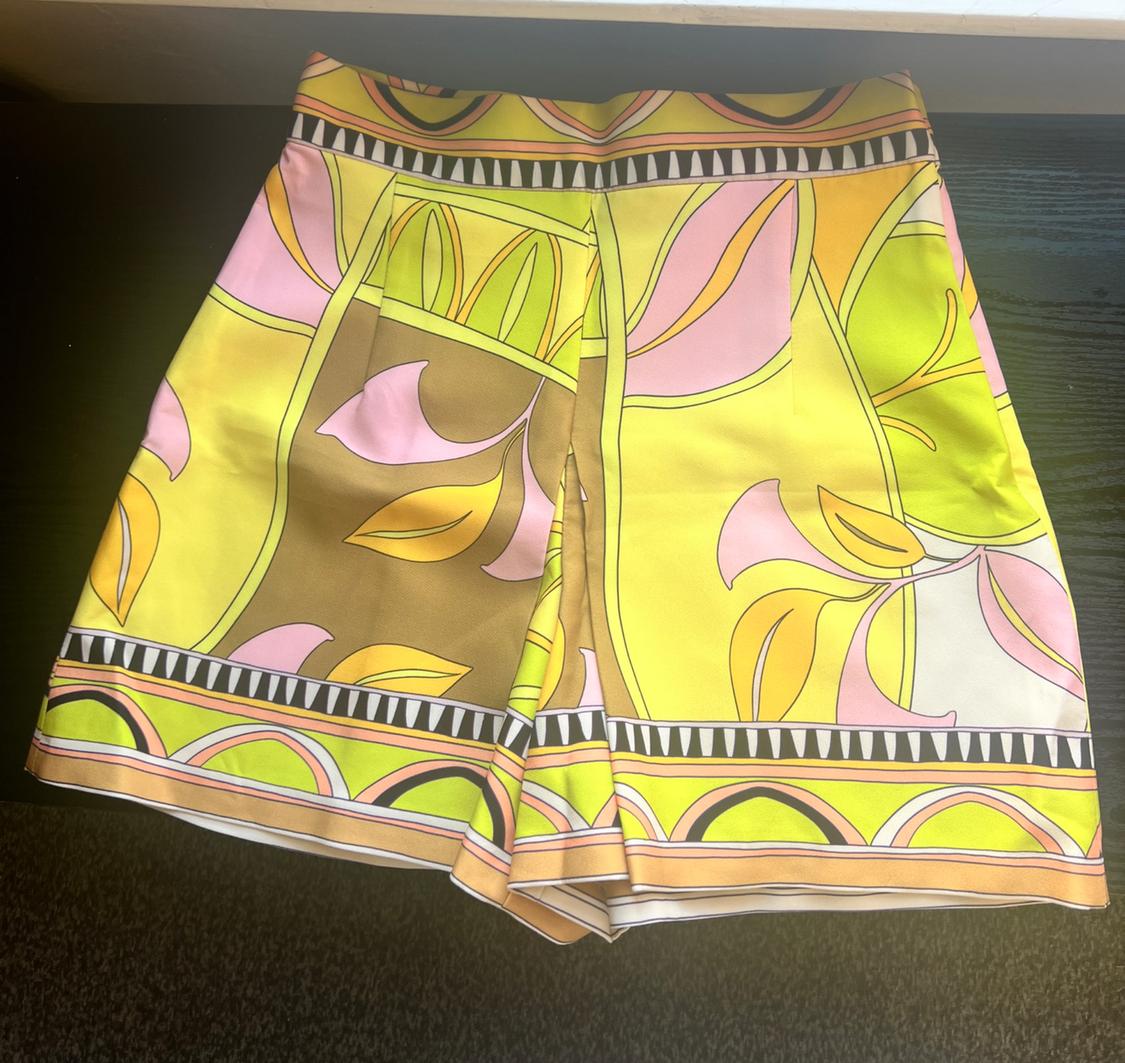 Shorts with a geometric and floral print in yellow, pink, and brown tones on a dark background.