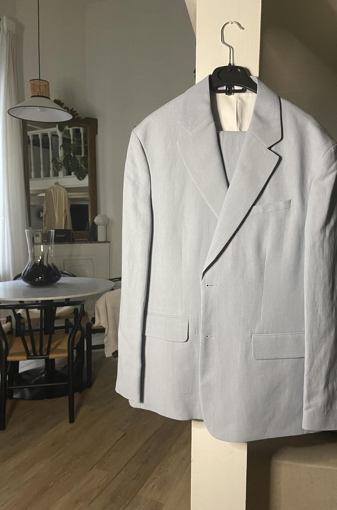 Front view of light grey jacket with lapels and front flap pockets.
