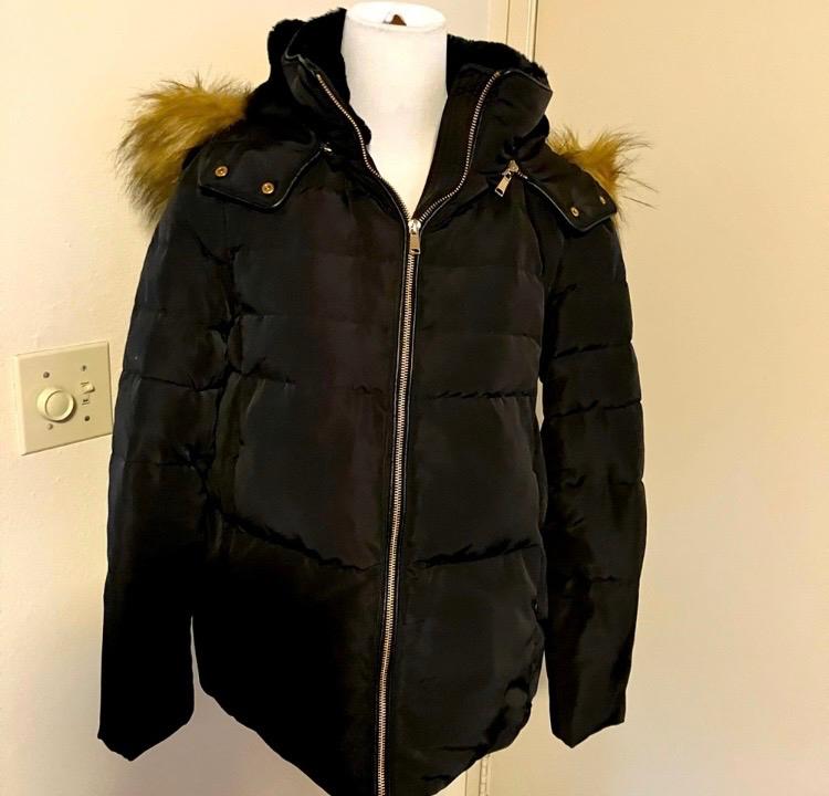 Black padded jacket with a hood and brown faux fur trim, displayed on a white mannequin against a light background.