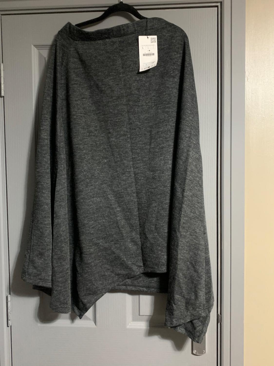 Grey cape hung on a hanger over a white door, with visible label at the top.
