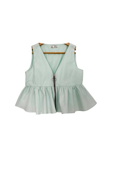 Front view of a light green waistcoat with a zip and ruffles at the hem.
