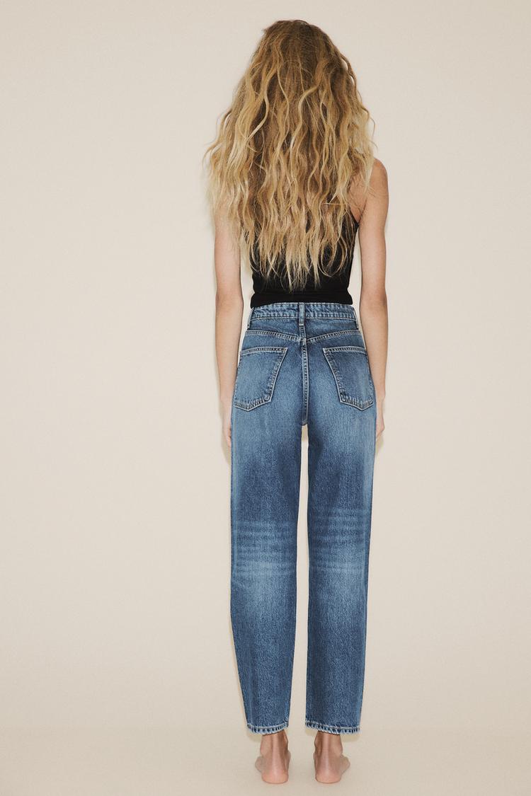 Komplet modrih kavbojk z visokim pasom, zadnjimi žepi in ravnim robom ter črnega topa brez rokavov.