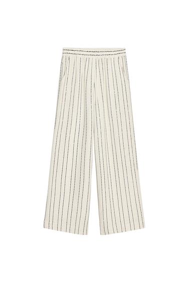 Front view of trousers with black and white vertical stripes, side pockets.