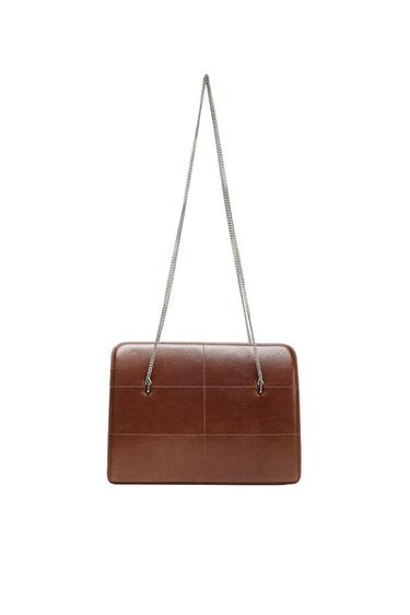 Brown rectangular textured handbag with panel-effect stitching. It features a silver chain strap against a white background.