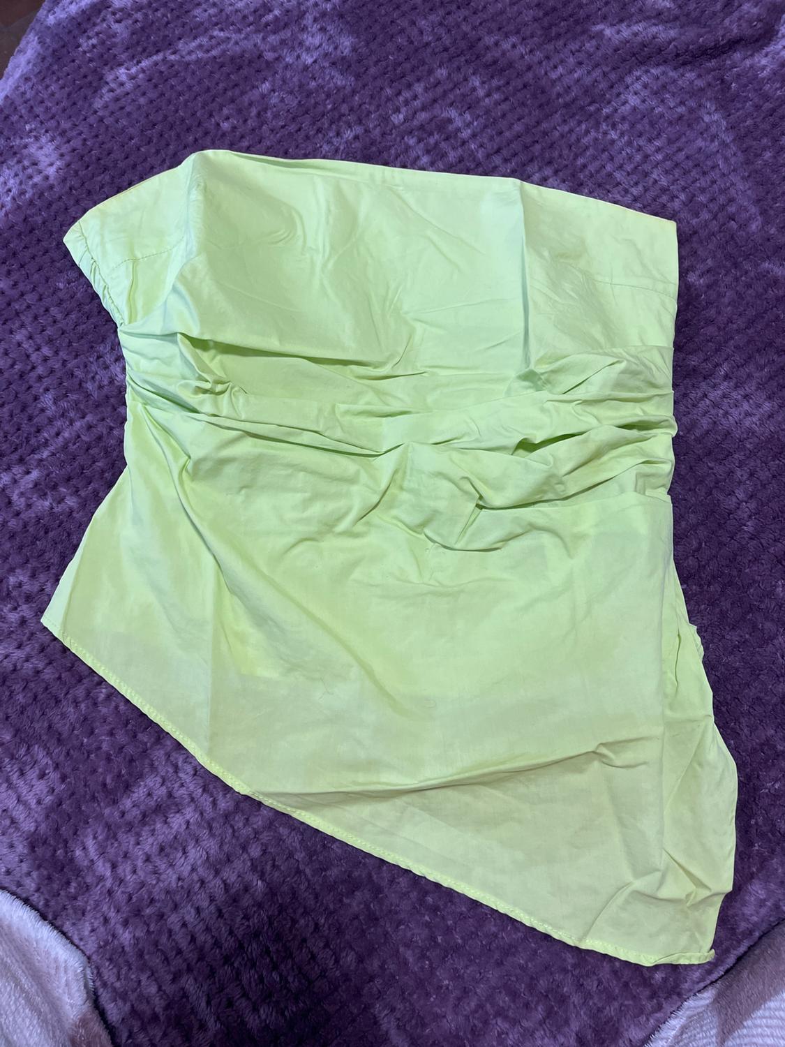 Yellow fabric draped over a textured purple blanket. The fabric has an asymmetrical design and is wrinkled.