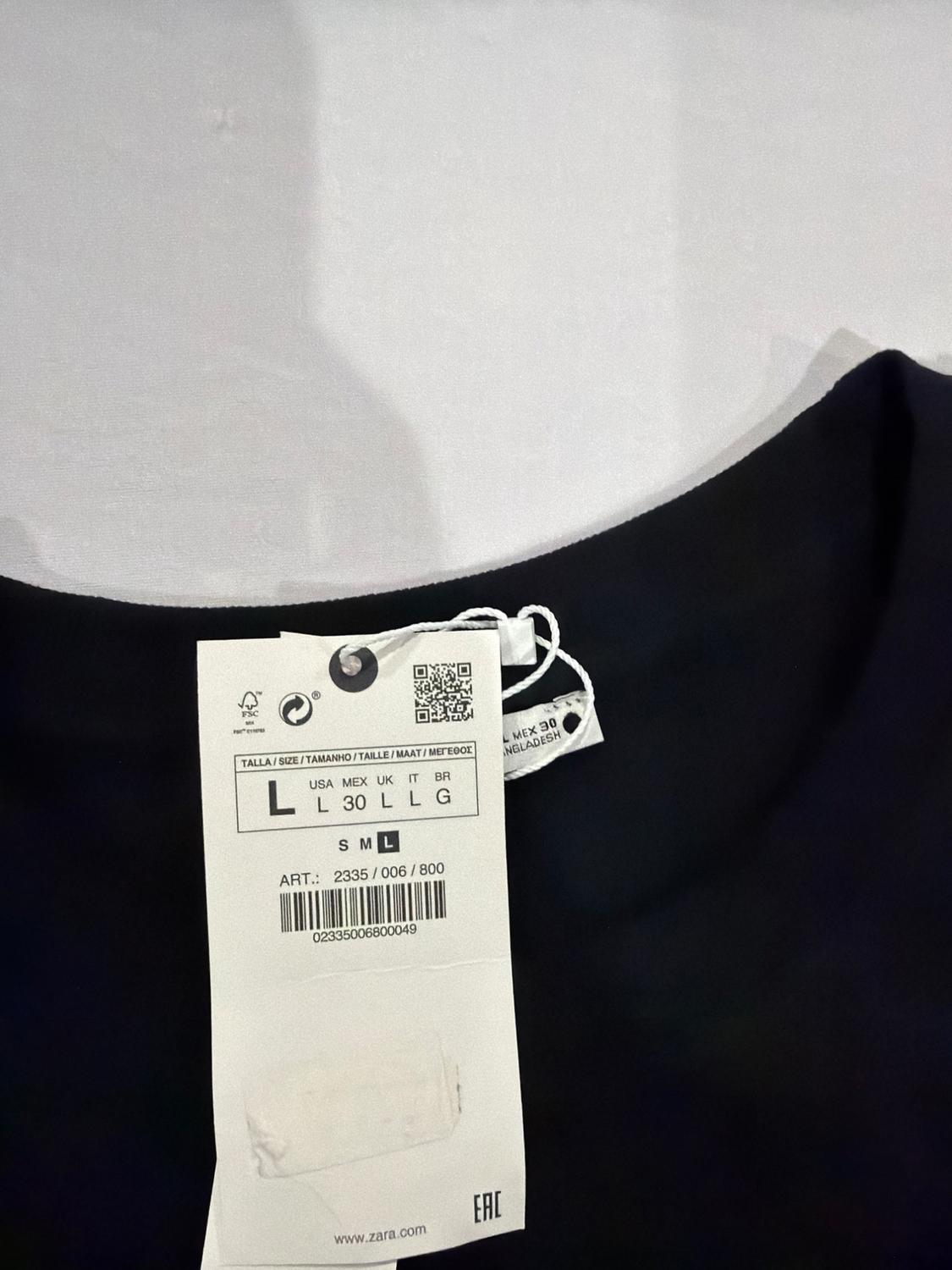 White label on the collar of a dark garment. Text: SIZE L USA L MEX 30 UK L IT L BR G ART.: 2335/006/800 EAC