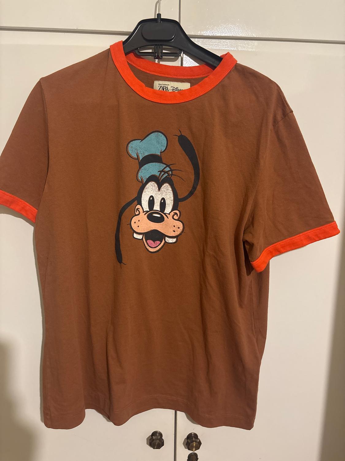 Brown T-shirt with orange trim, animated character print with blue cap. Visible tag: "Zara Disney".