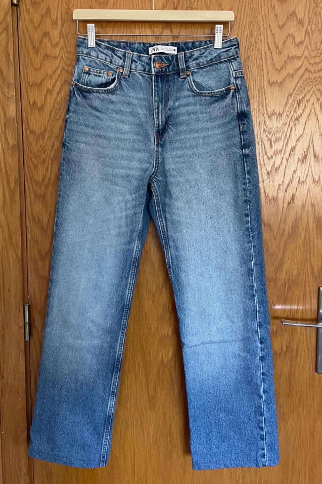 Front view of blue denim jeans with front pockets and a visible button.