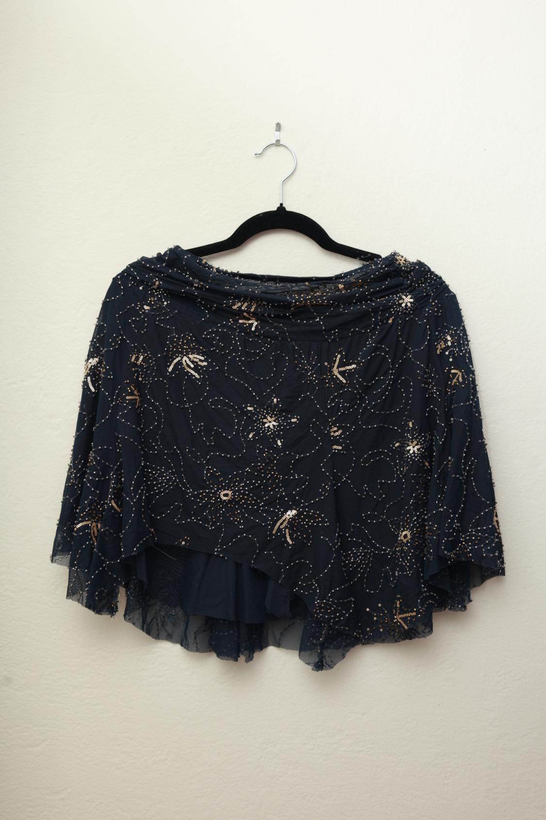 Semi-sheer navy blue top with gold sequin floral embroidery, hanging on a black hanger against a white background.
