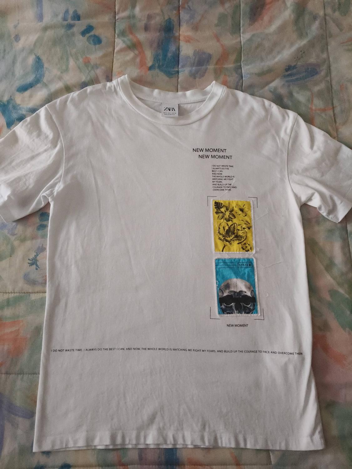 White t-shirt with rectangular yellow and blue prints. Text: "NEW MOMENT" and "I DO NOT WASTE TIME..." on a colourful background.