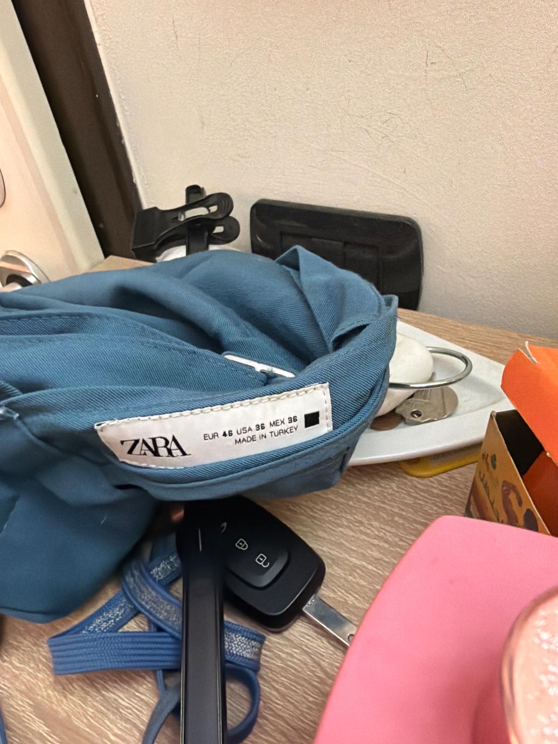 Blue garment on a table next to some keys. Its label reads: ZARA EUR 46 USA 36 MEX 36 MADE IN TURKEY.