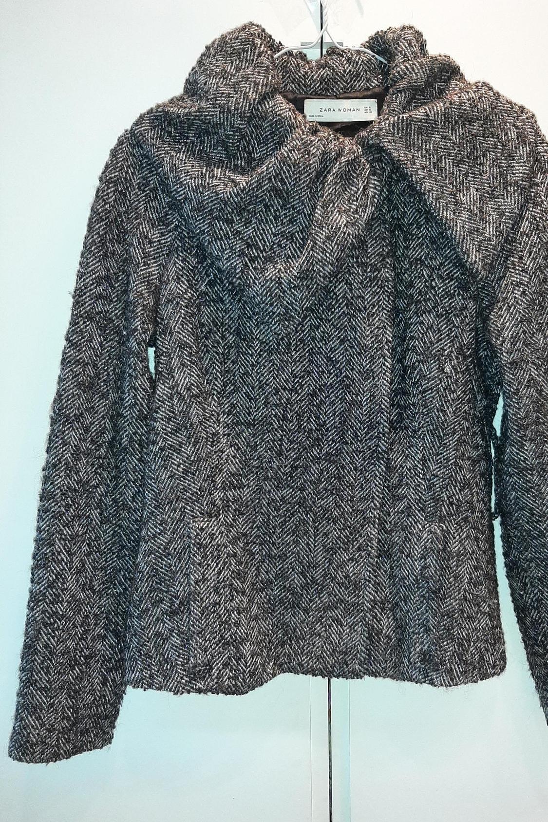 Front view of a grey jacket with a herringbone pattern and high neck.