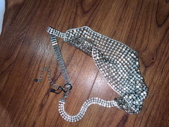 Silver chain necklace with brilliant-cut inlays on a brown wooden surface.