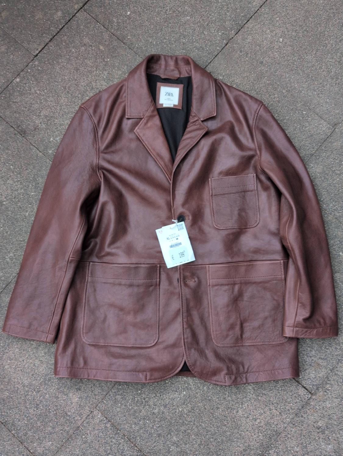 Brown leather jacket on a tiled floor. Inner label with ZARA text and outer label with XL text and € 199.