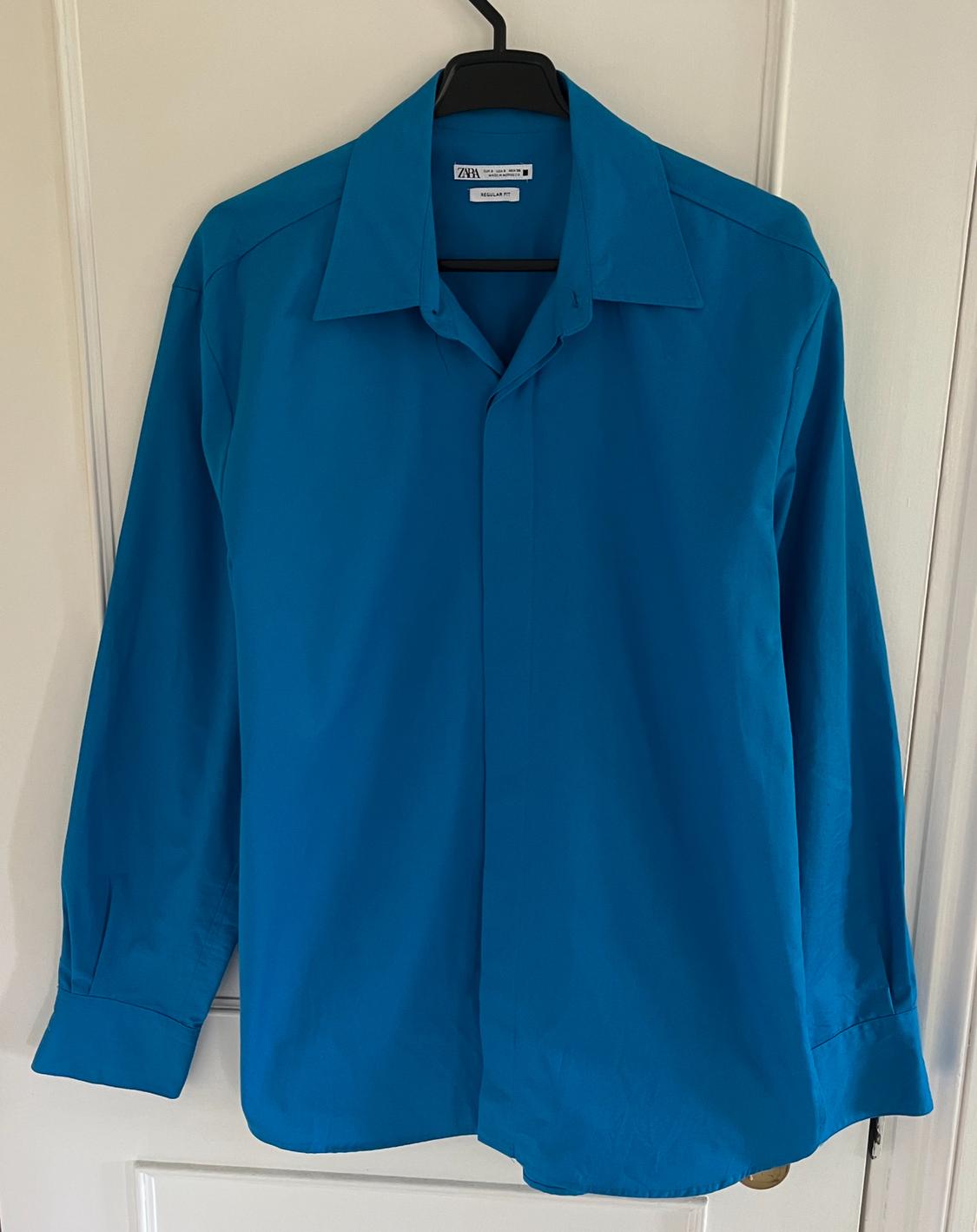 Front view of a blue shirt with a classic collar and long sleeves.