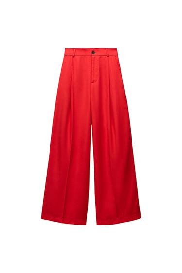 Front view of wide-leg red trousers with a high waist and visible button.
