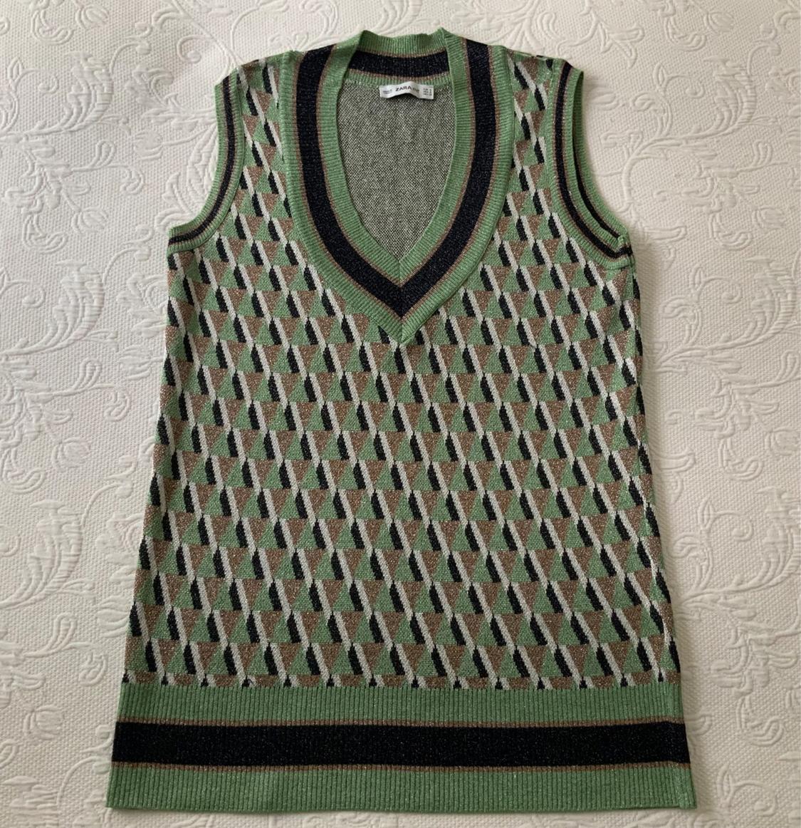 Sleeveless waistcoat with a geometric pattern in green and black tones on a textured white background. V-neck and green trim.