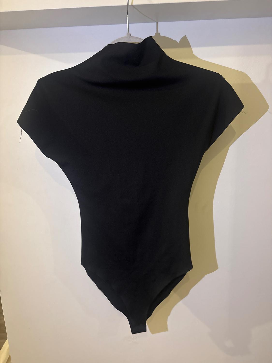 Black short-sleeved high-neck bodysuit hanging on a hanger against a white background with a drop shadow.