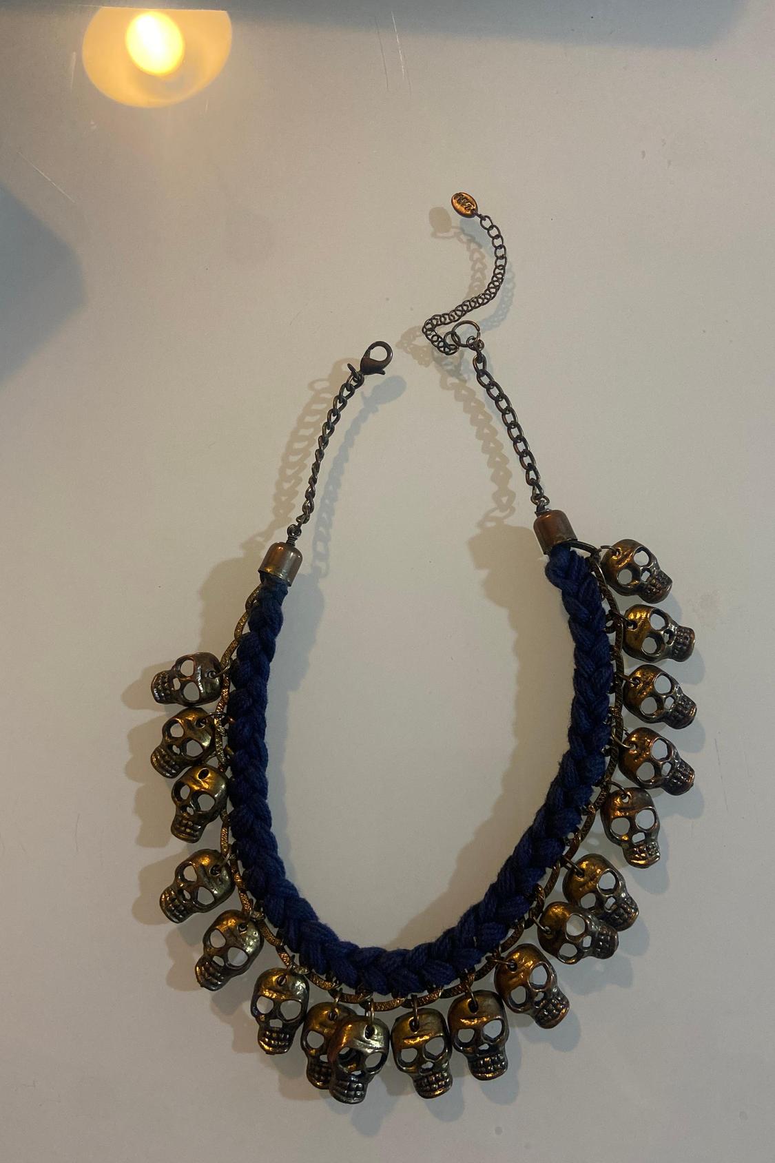 Necklace with chain and dangling skulls in bronze on a white background.